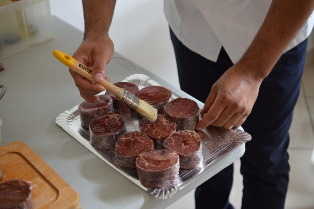Le chef Michel Hélène badijonne la viande avant la cuisson