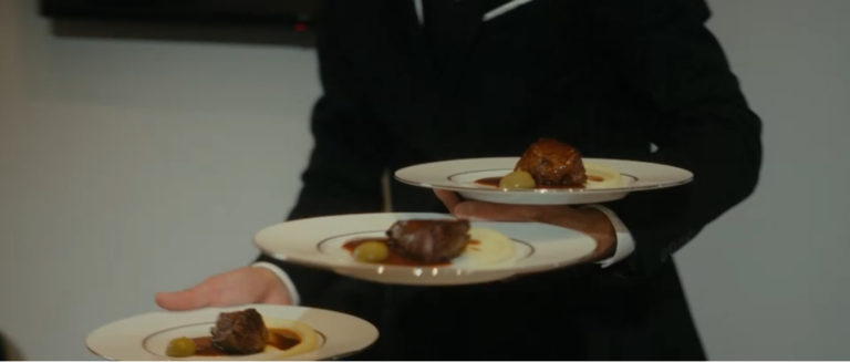 Un maître d'hôtel en train de servir un plat de viande lors d'un dîner à domicile à Paris