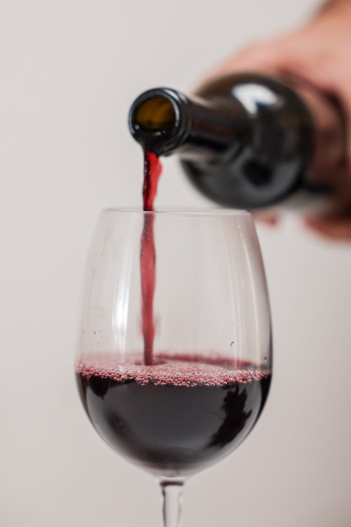 Gros plan d’un verre de vin rouge en train d’être servi. Idéal pour des thématiques liées au vin