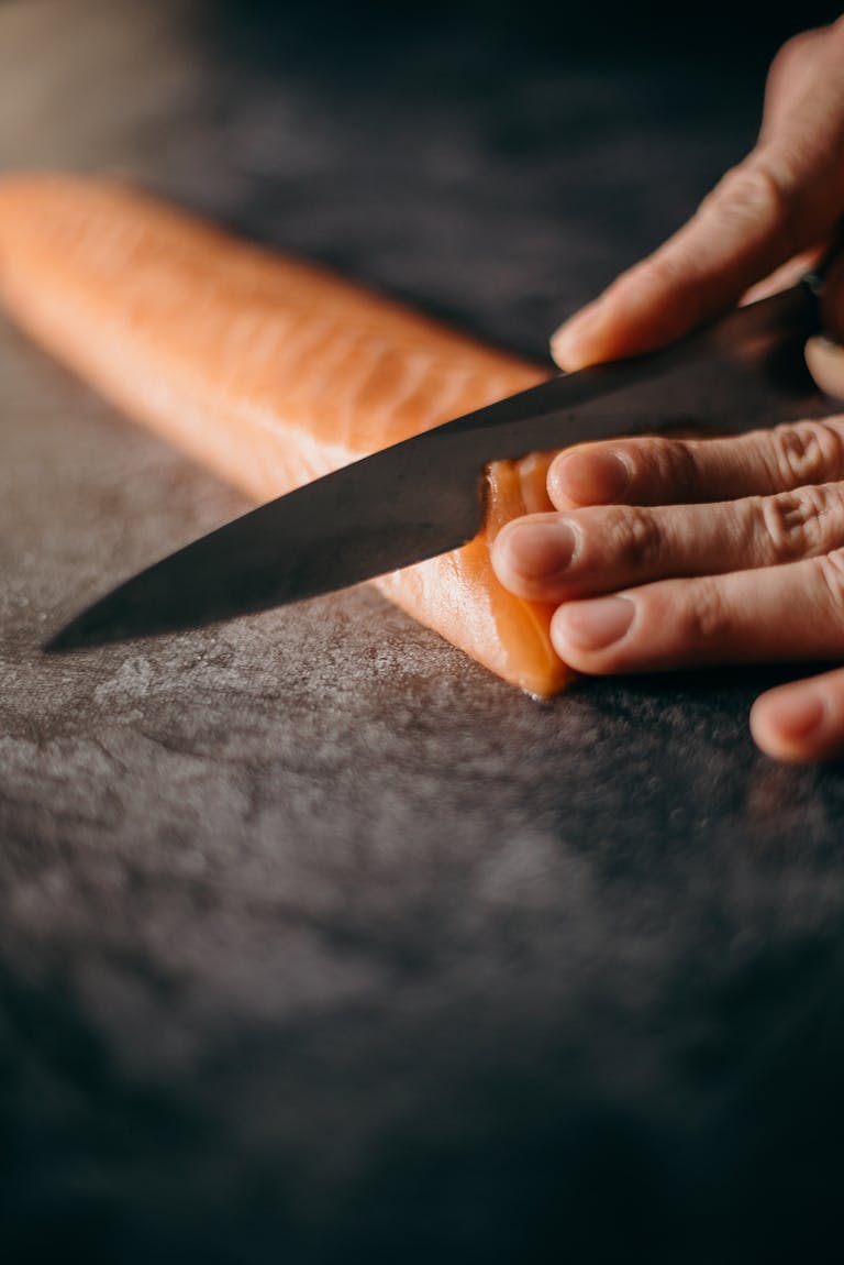 Le chef à domicile entrain de couper un saumon gravelax