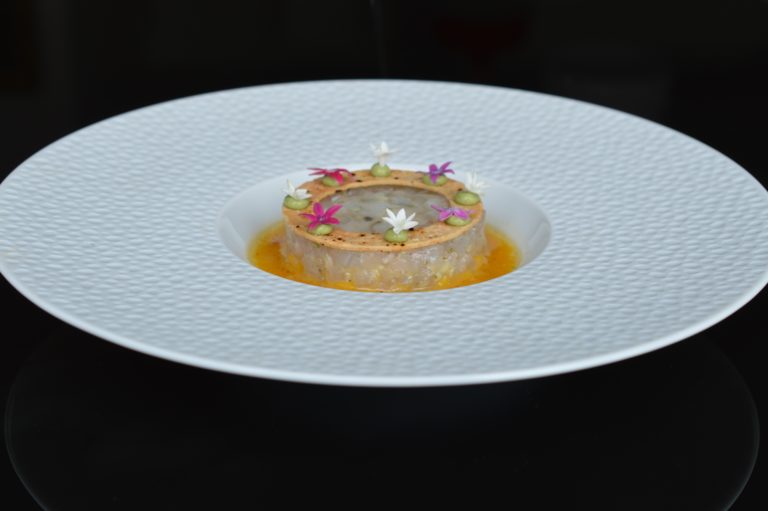 Tartare de bar sur une assiette creuse et un fond noir