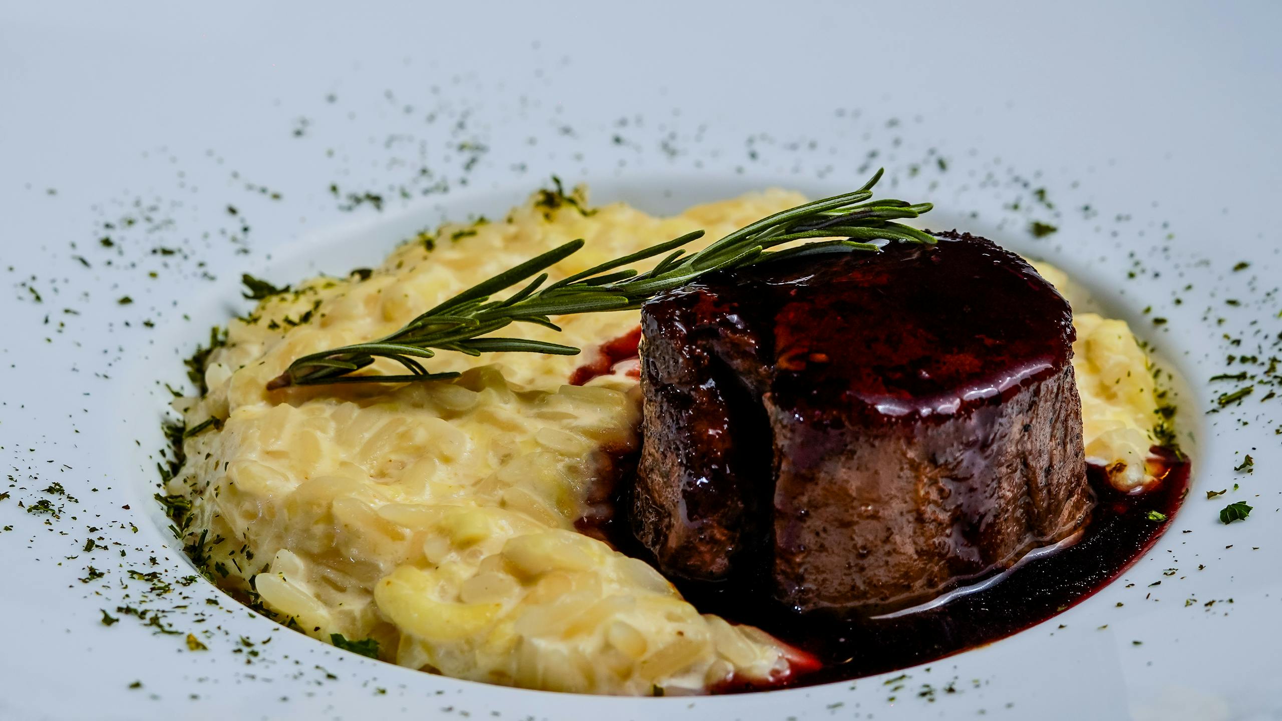 Un délicieux steak d'agneau accompagné d'un risotto crémeux et garni de romarin, parfait pour un repas gastronomique.