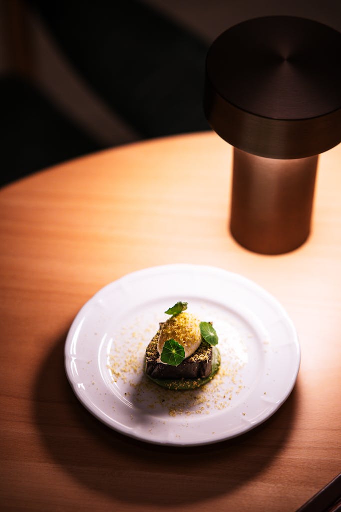 Un plat gastronomique élégamment présenté sur une assiette blanche sous un éclairage d'ambiance chaleureux, créant une atmosphère conviviale pour dîner.