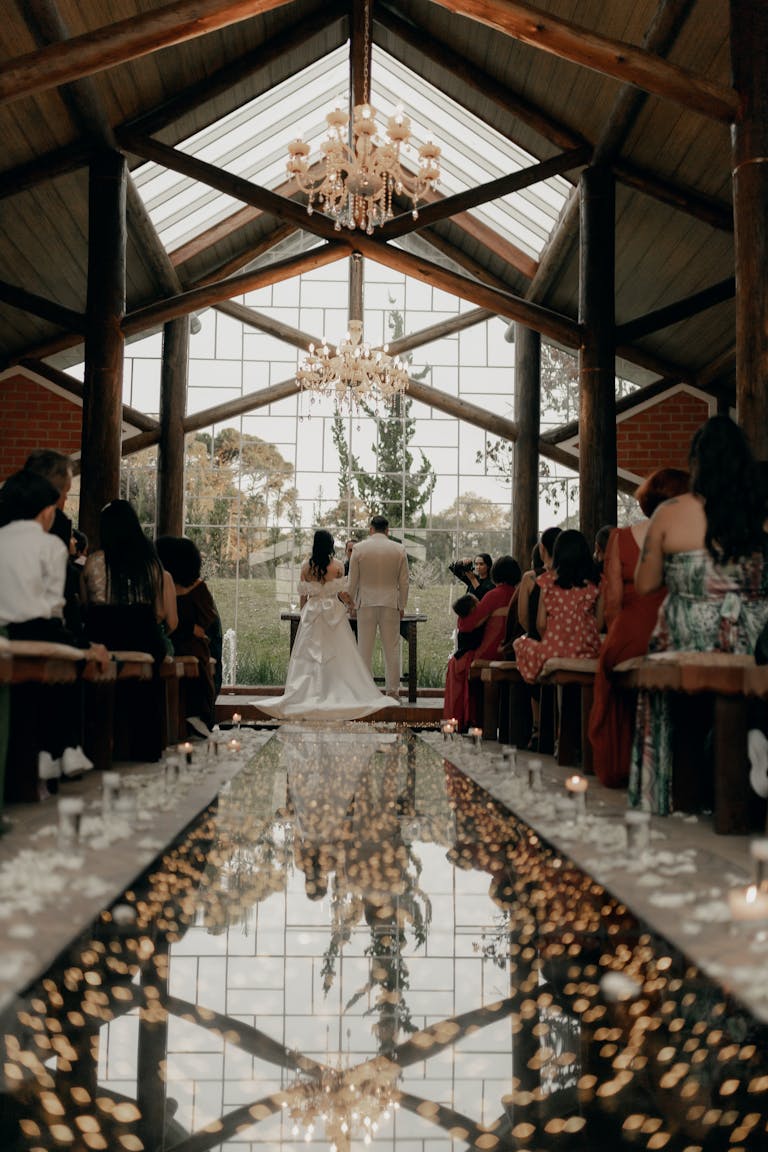 Magnifique cérémonie de mariage en intérieur, avec un élégant lustre et une allée miroitante.