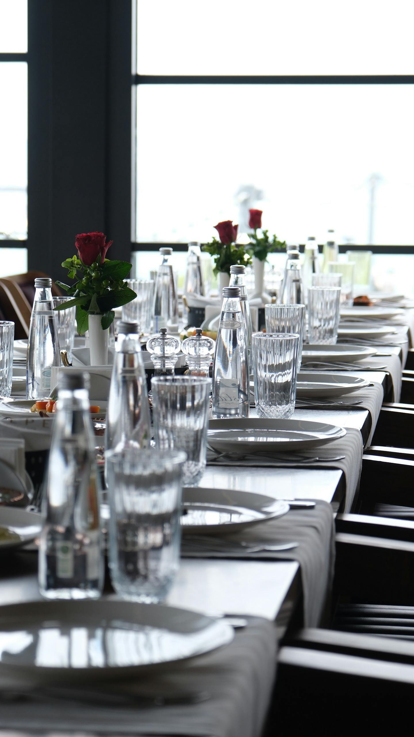Une table élégamment dressée avec de la verrerie et des roses rouges lors d'un dîner privé